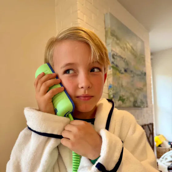 A boy in a bathrobe holding an Answer Me Aquamarine Tin Can to his ear
