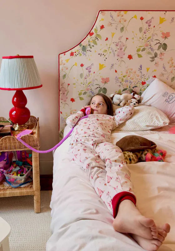 A girl in pajamas lying on her bed, talking on a Later Alligator Lilac Tin Can landline