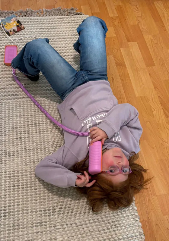 A girl lying upside down on a rug, chatting on a Later Alligator Lilac Tin Can