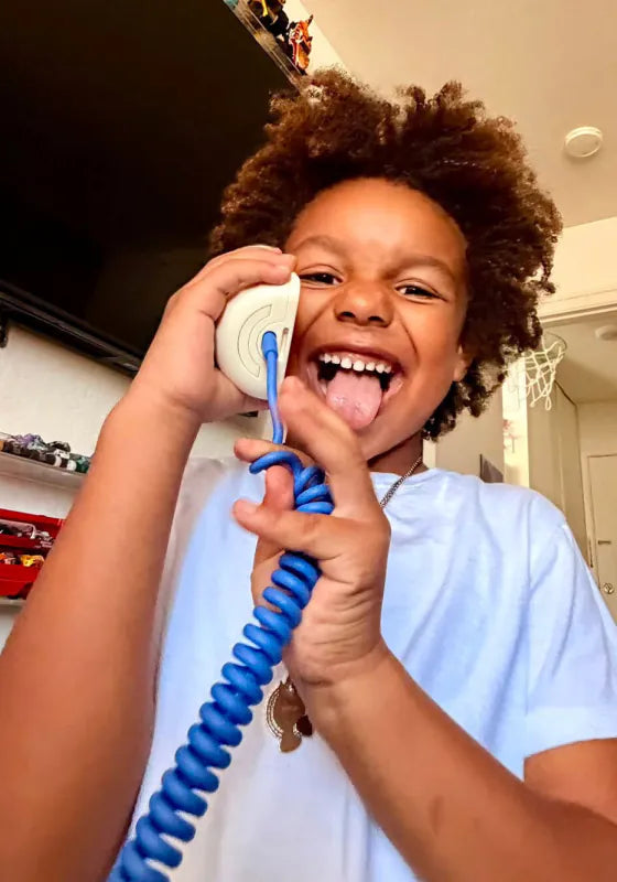 A laughing boy sticking out his tongue, holding a Static White Tin Can handset