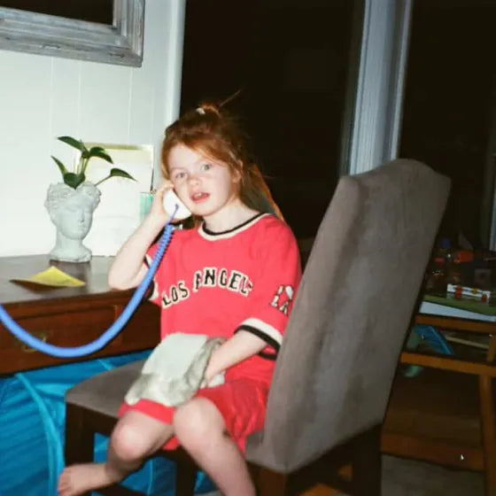 A girl in a Los Angeles jersey sitting at a desk, chatting on her Static White Tin Can landline